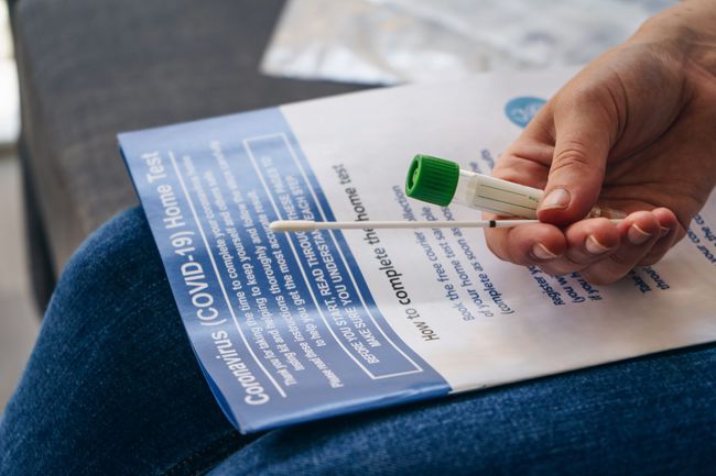 An image of a woman holding an at home COVID-19 test.