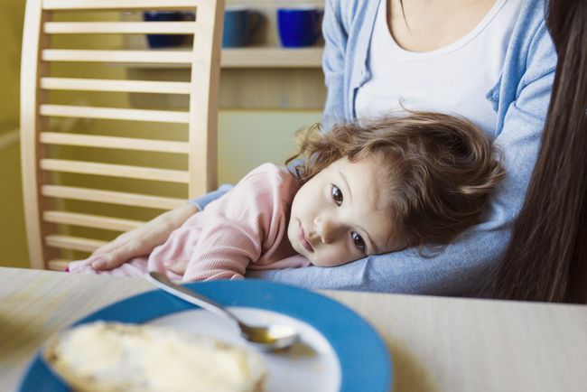 little girl in her mother's arms at breakfast table