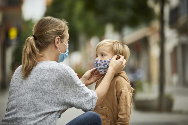 An image of a mo putting a mask on her daughter.