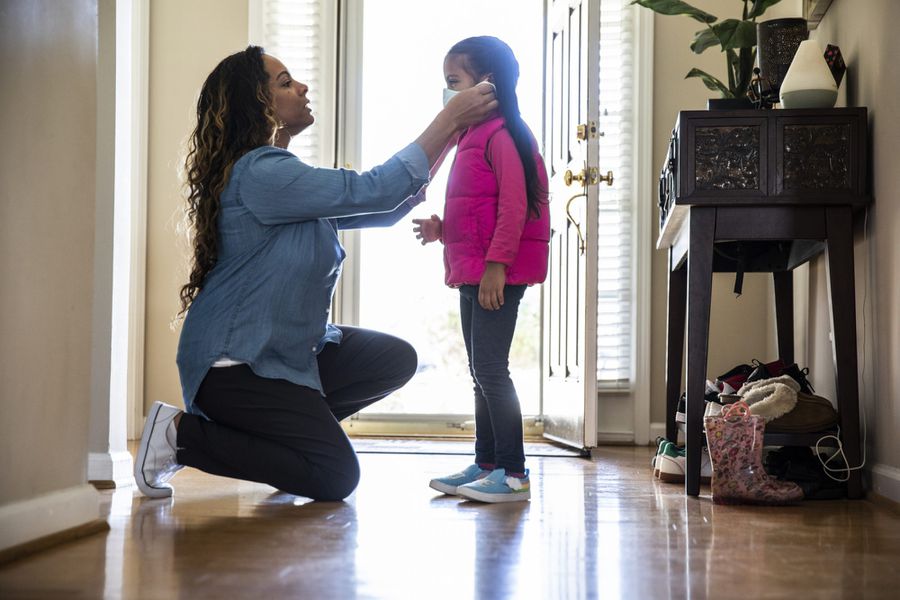 An image of a mother putting mask on daughter.