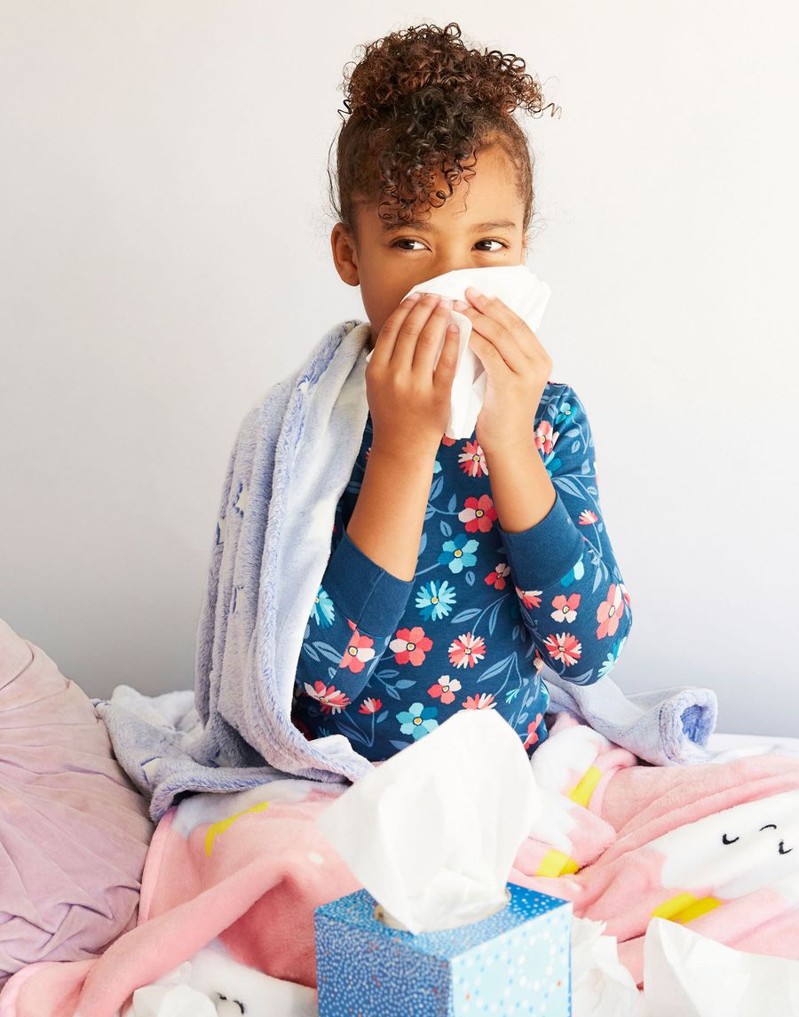 little girl in bed with kleenex box blowing her nose