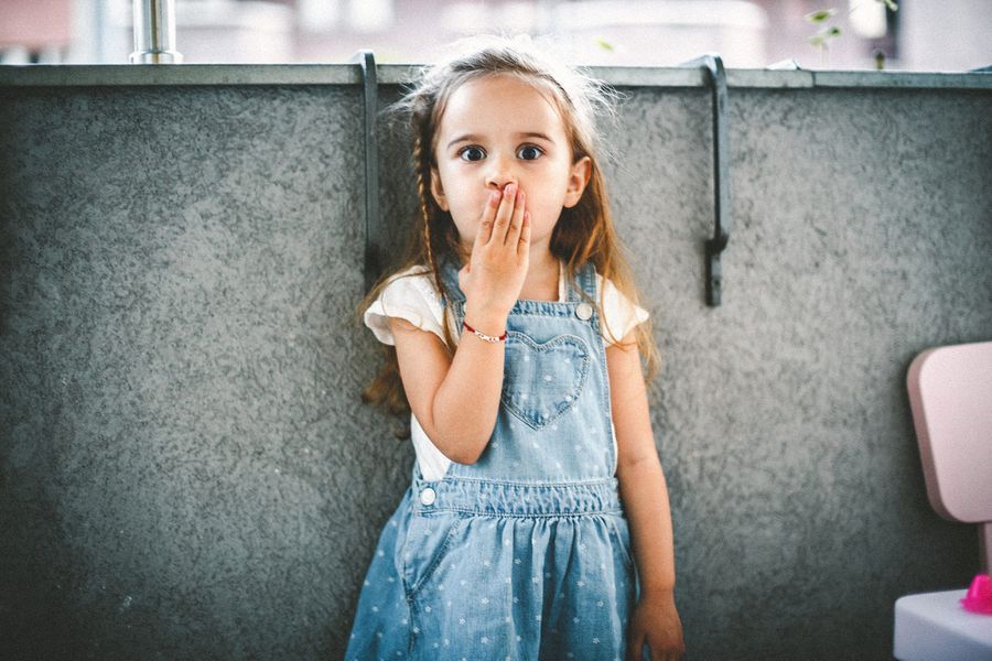 little girl with hand over mouth