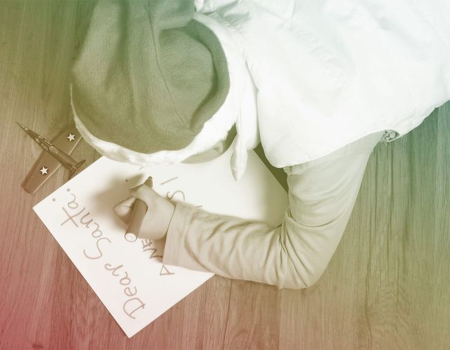 child wearing santa hat writing letter to santa