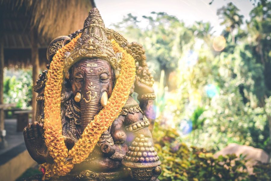 A bronze Ganesh statue, with a yellow garland.