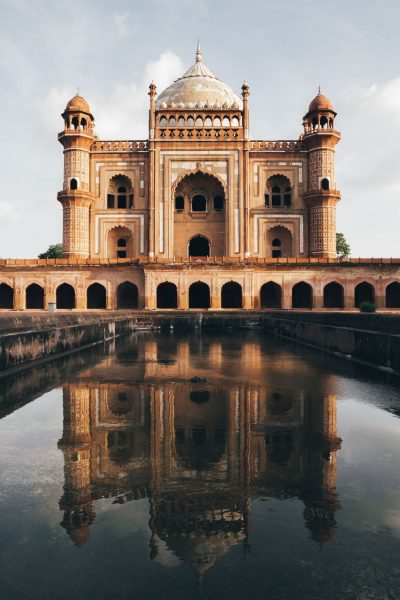 A large red and white domed building and it's reflection in water.