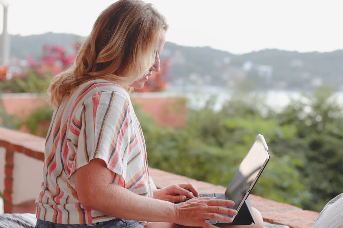 Chel Rogerson in profile working on her laptop on a balcony