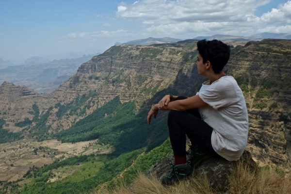 Woman sitting cliffside with view of the Simien Mountains of Ethiopia