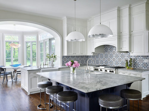 White kitchen with blue backsplash and a large kitchen island with gray and white marbled top