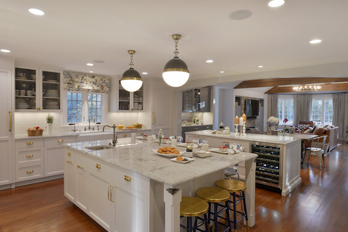 Bright white kitchen with gold fixtures and two islands