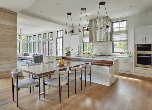 White kitchen with island that has dining table attached