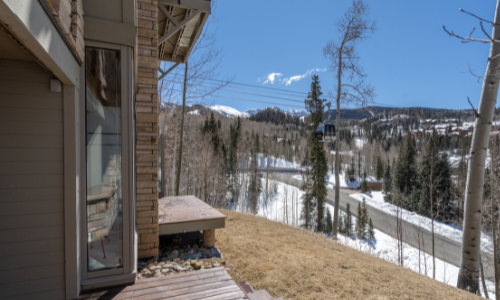 A beige and brown home with a ski slope access in the distance